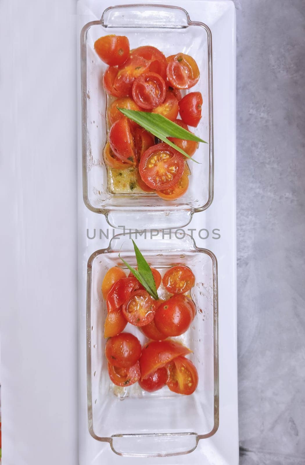 Delicious appetizer of cherry tomatoes in glass plates on a white background