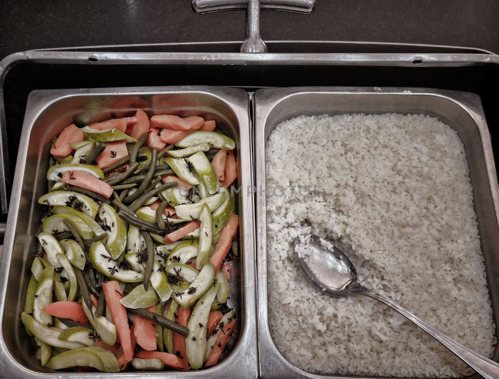 Buffet-style catering in the hotel restaurant. The design of the dishes and the concept of serving dishes in the restaurant. There are a variety of vegetables and rice in metal containers