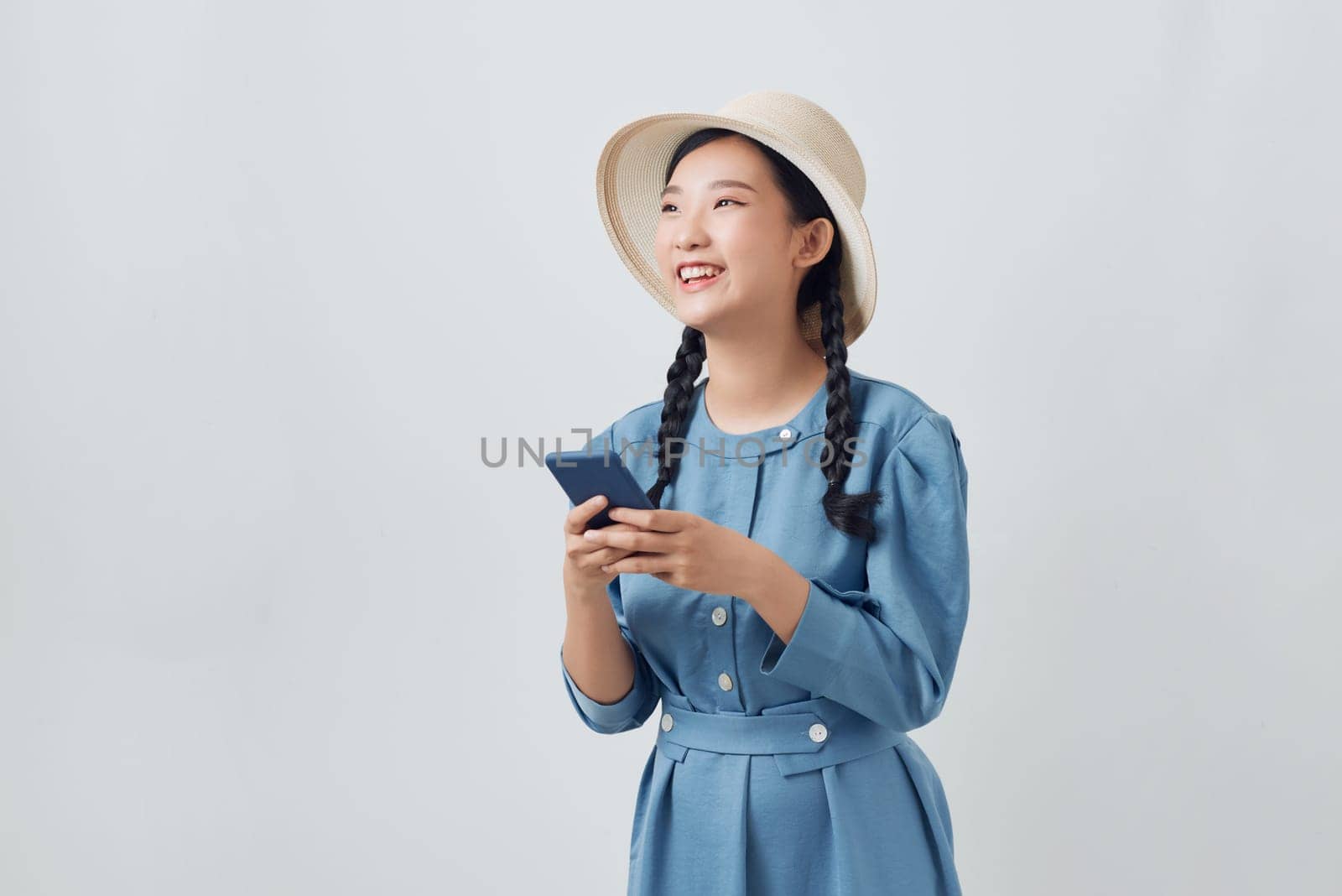 Smiling woman in denim dress using mobile phone by makidotvn
