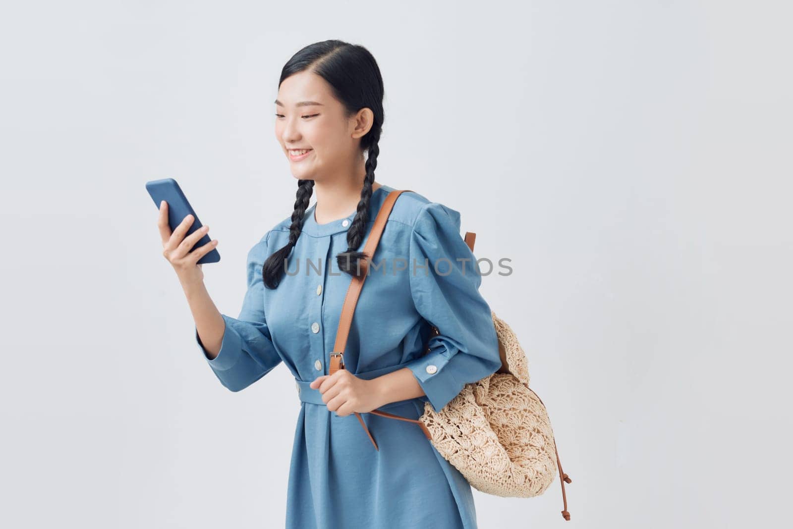 Smiling woman in denim dress using mobile phone by makidotvn