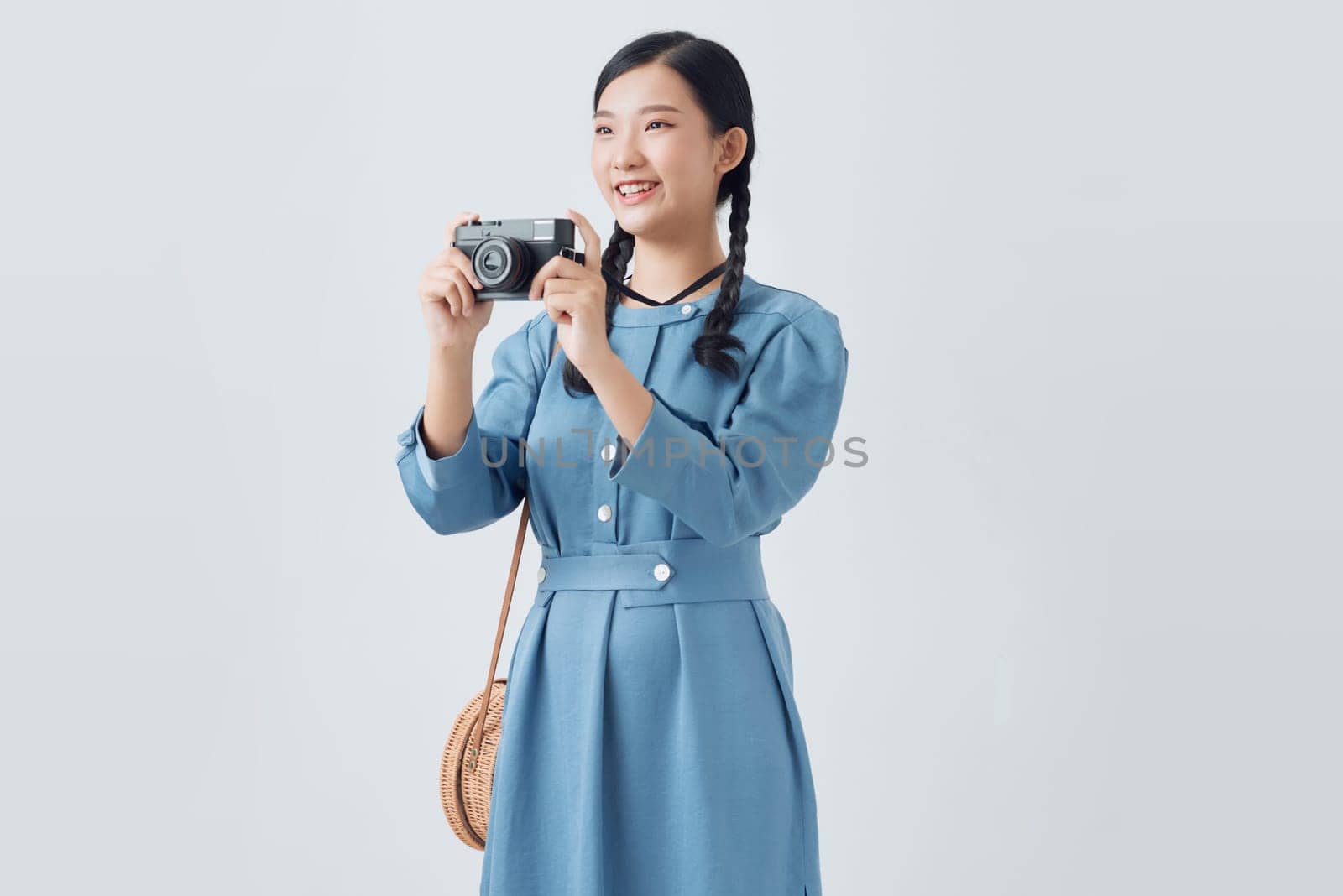 Young girl taking a picture with a small camera on a white background