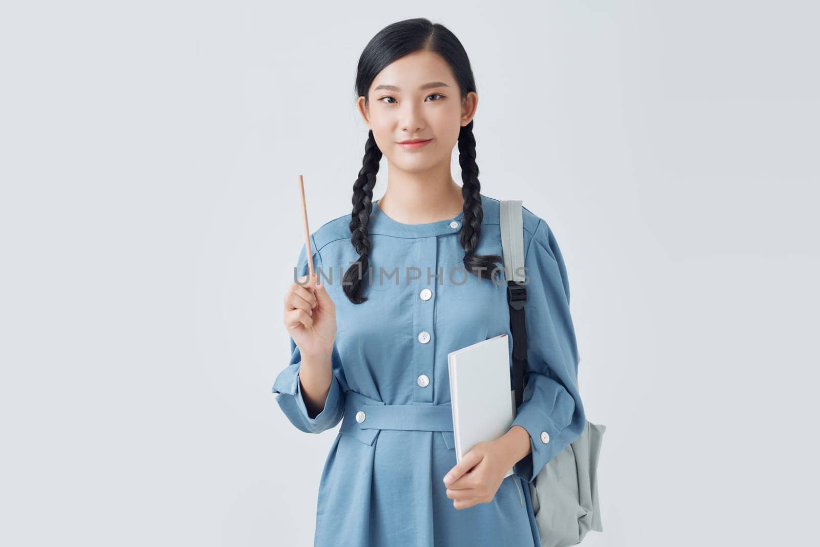  Cheerful attractive asian girl with backpack making notes in notebook isolated on a white background by makidotvn