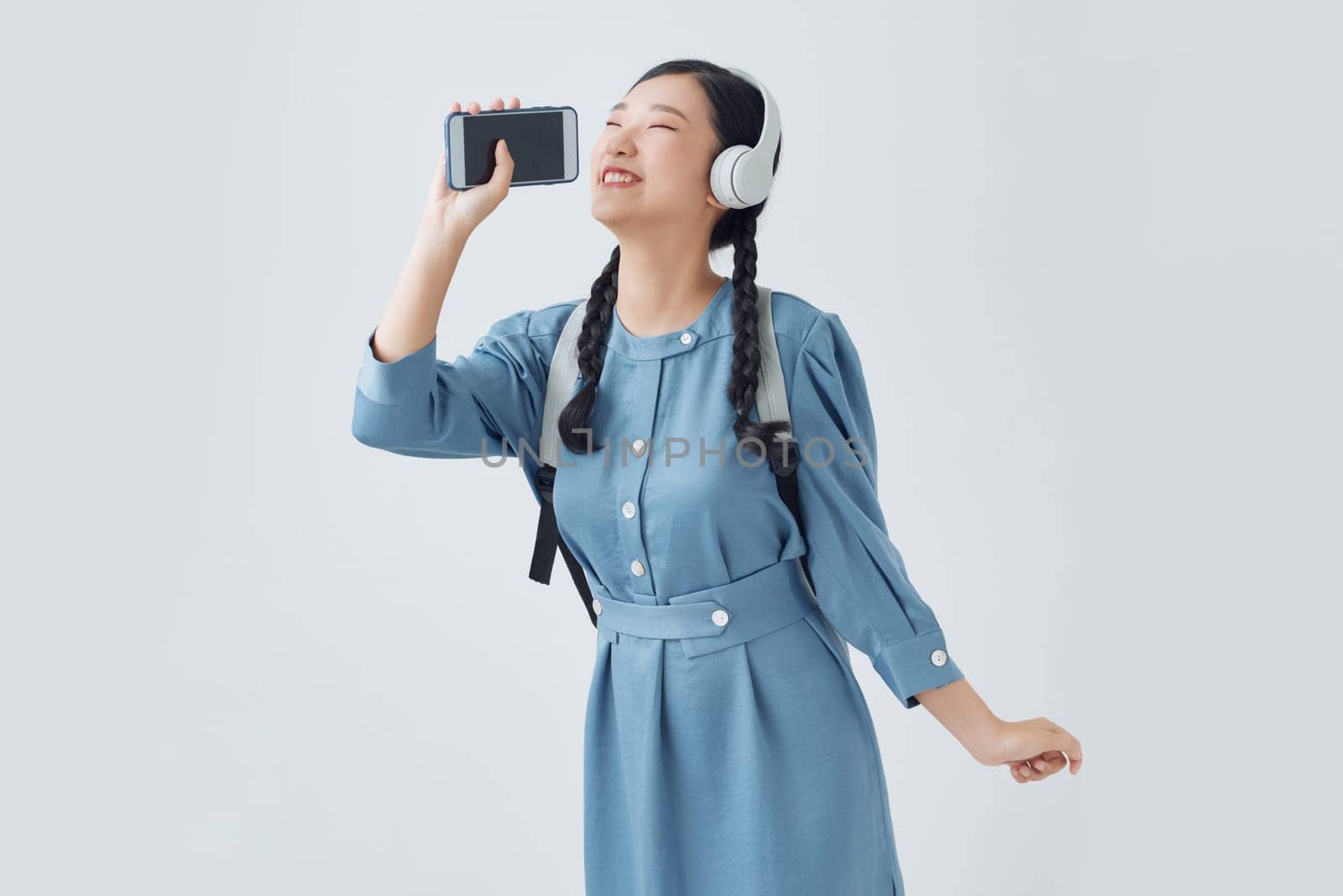 Excited emotional asian woman singing her favorite song, using smartphone as microphone by makidotvn