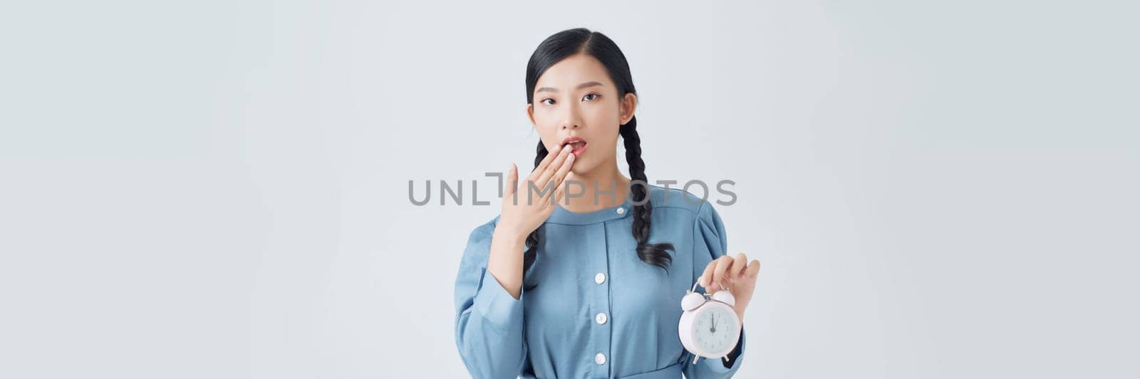 Young Asian woman is stressed with a clock on white background by makidotvn