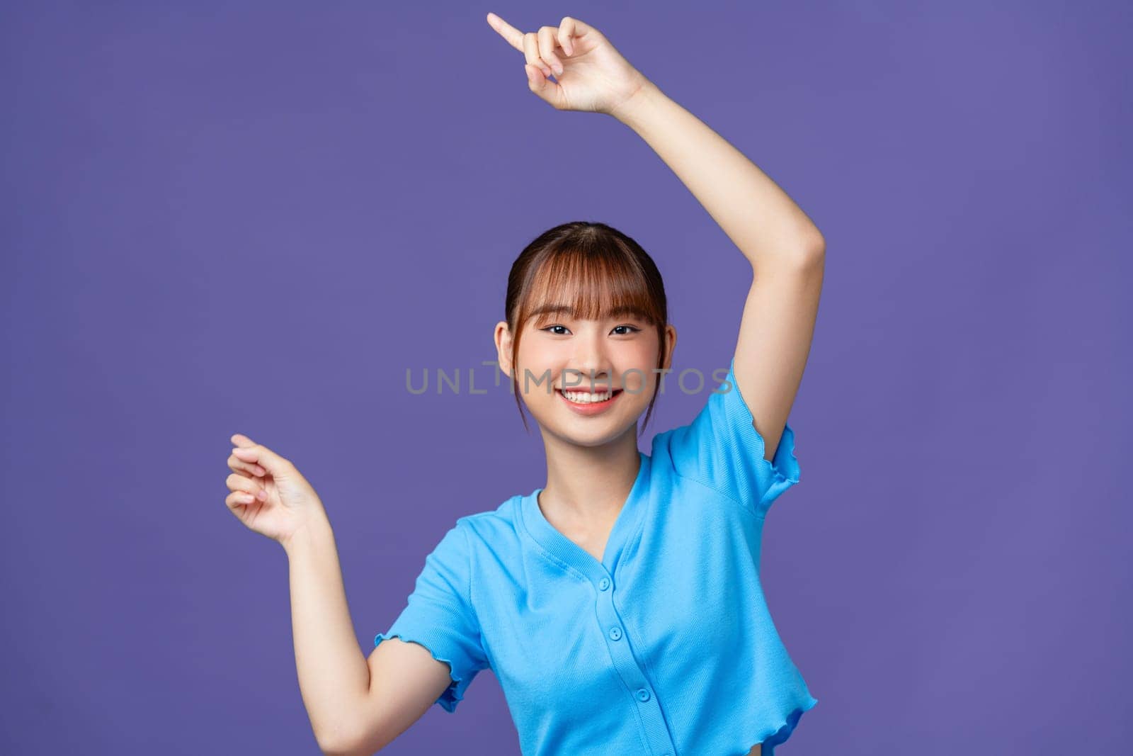 Asian beautiful young woman pointing both hands with finger on upper side with smile face.  by makidotvn