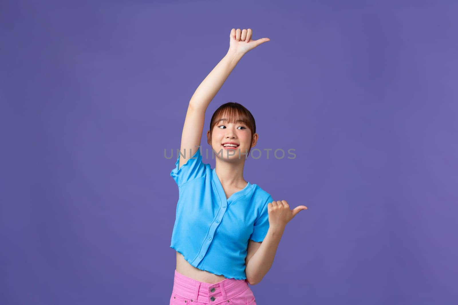 Young asian woman smiling with happy face looking and pointing to side with finger up.