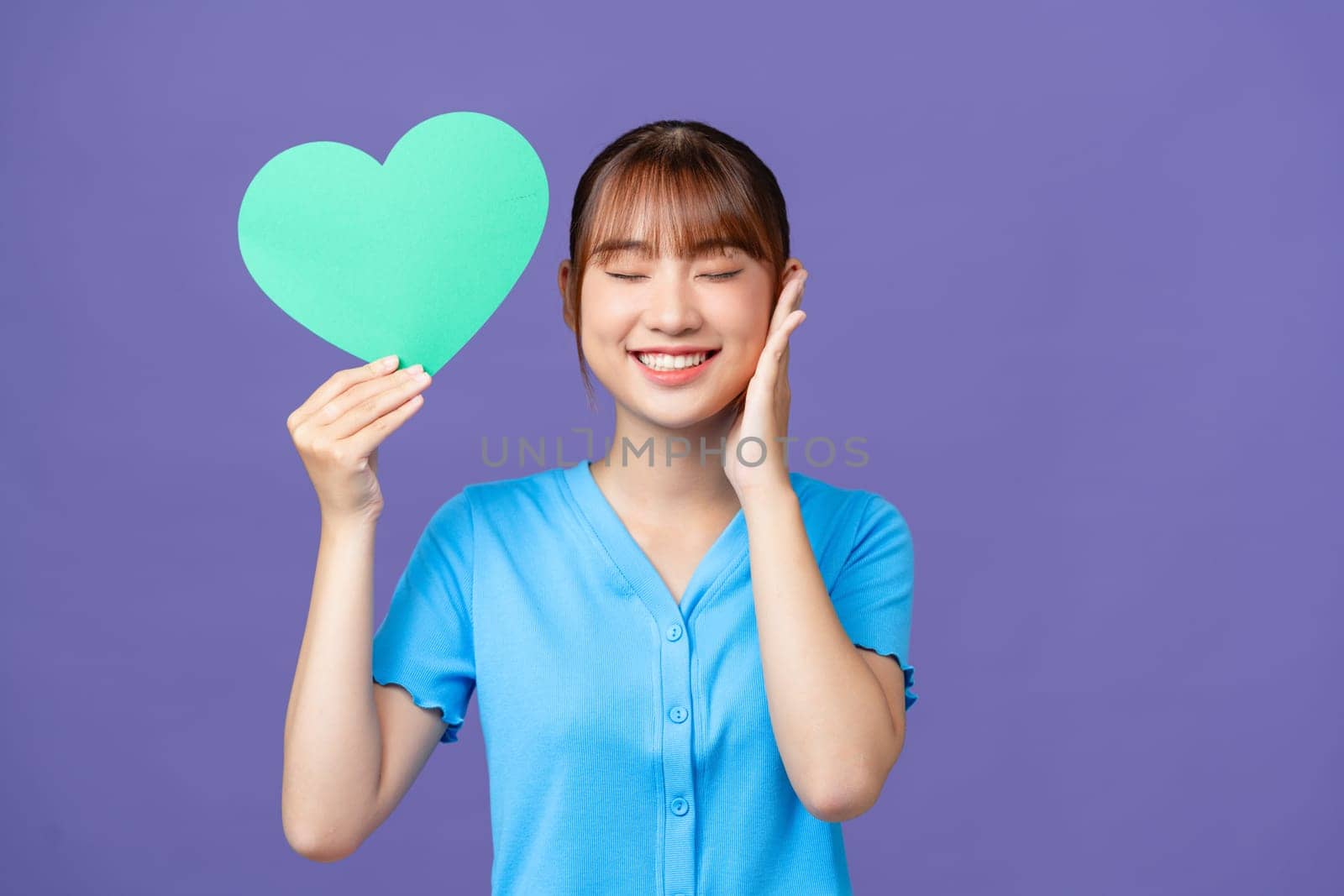 Portrait of cheerful person hold heart postcard toothy smile isolated on violet color background by makidotvn
