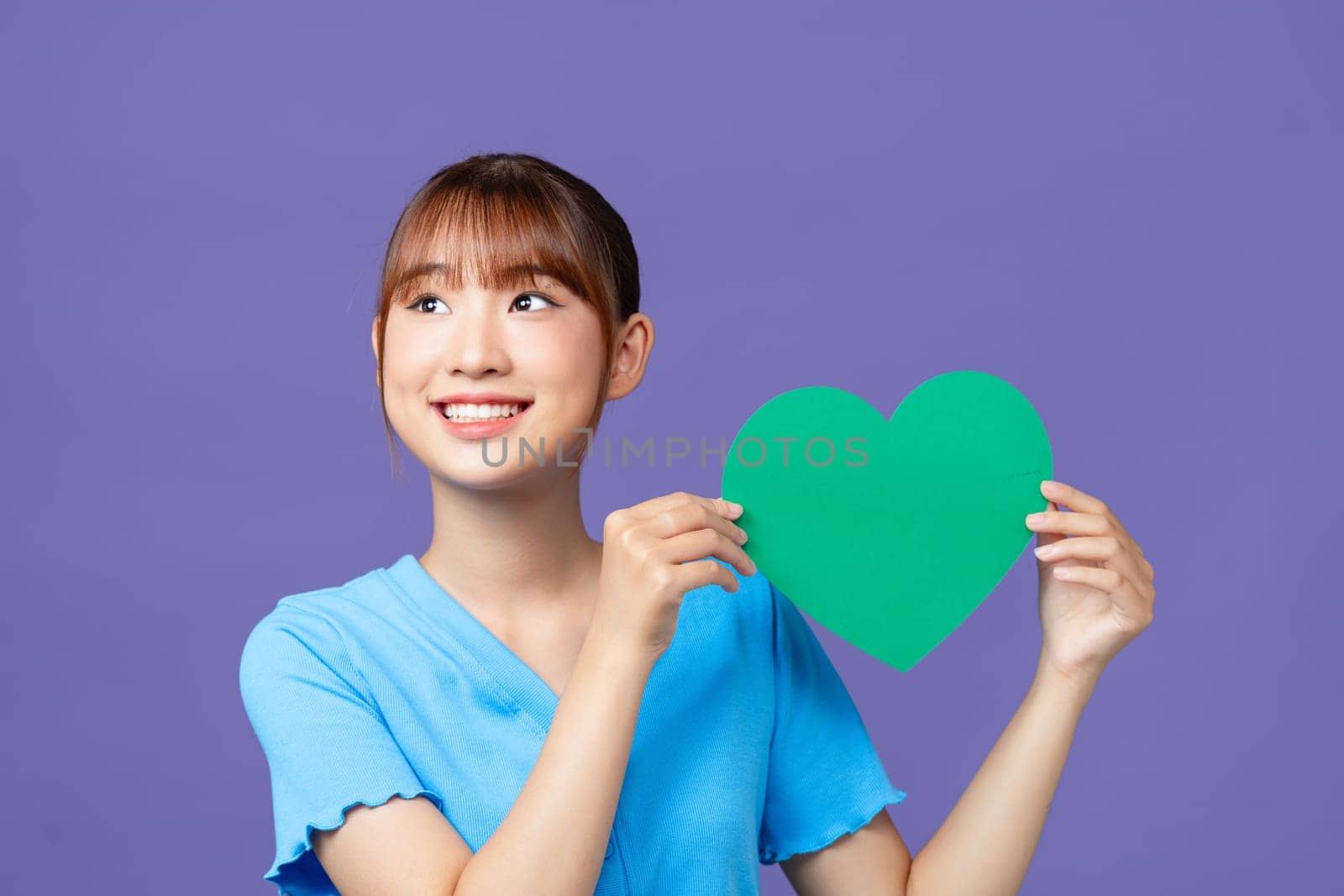 Portrait of cheerful person hold heart postcard toothy smile isolated on violet color background by makidotvn