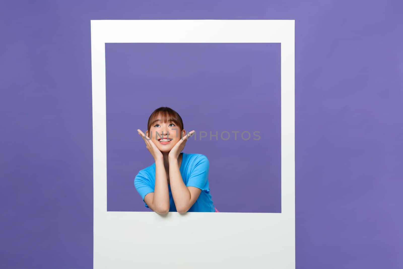 Cute young lady toothy smile hold white photo frame dressed trendy blue clothes