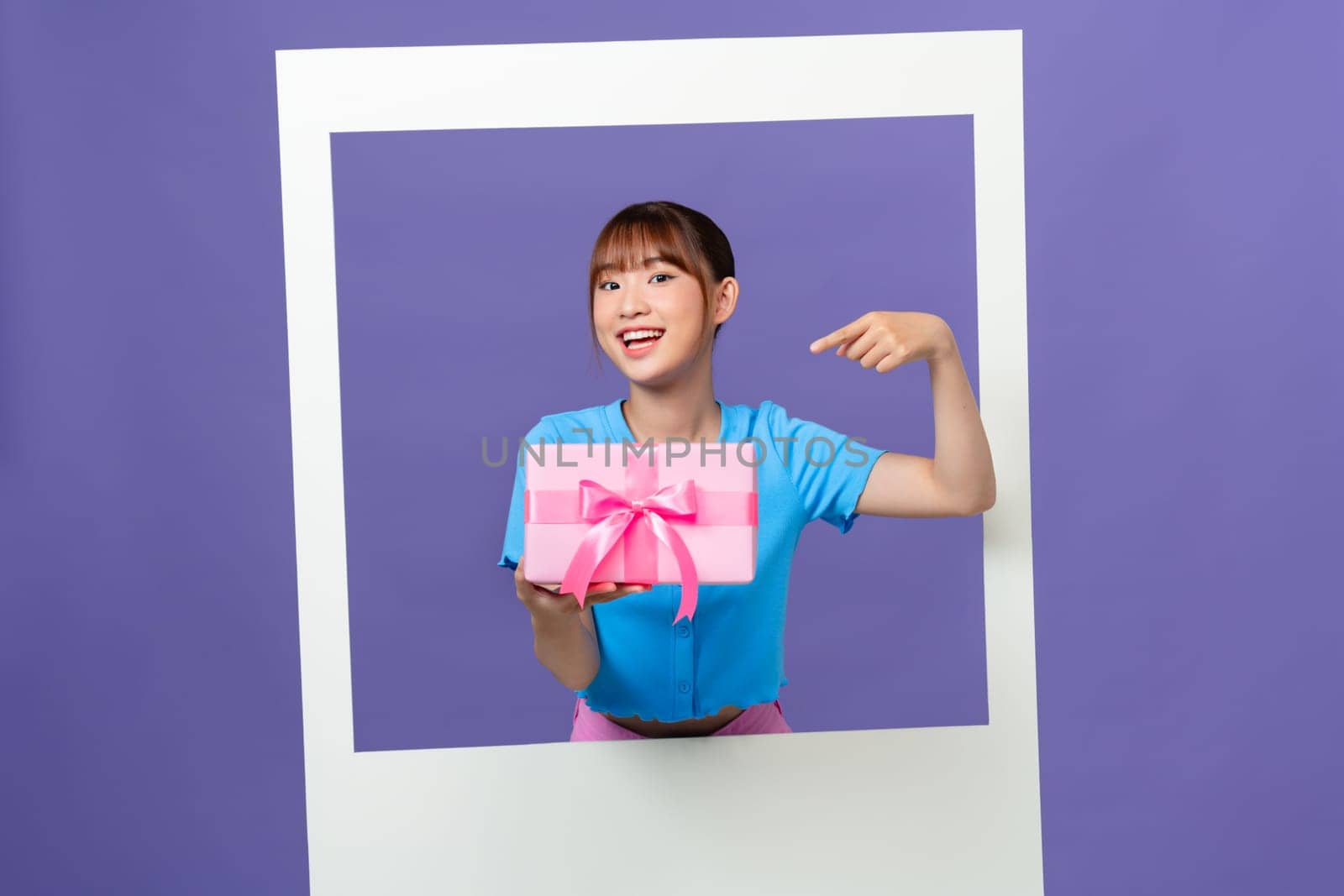Photo of funny excited young woman holding giftbox inside white photo frame over color background by makidotvn