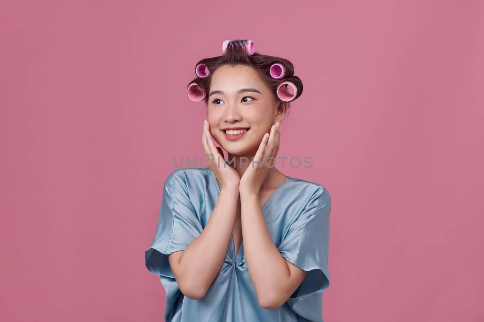 Hairdressing. Happy woman applying hair rollers on beautiful healthy hair