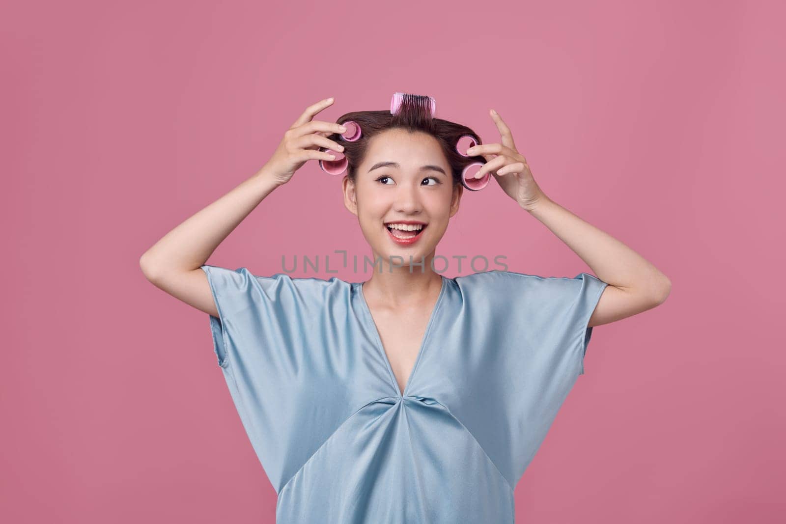 Cheerful asian girl with hair curlers rollers by hairdresser. by makidotvn