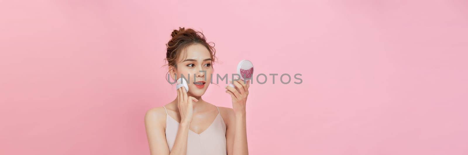 Face make up concept. Portrait of gorgeous young girl applying dry powder foundation by makidotvn