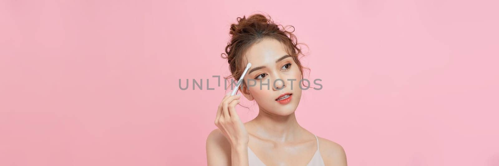 Beautiful young fresh happy girl with a cute smile holds a brush near face on a pink background by makidotvn