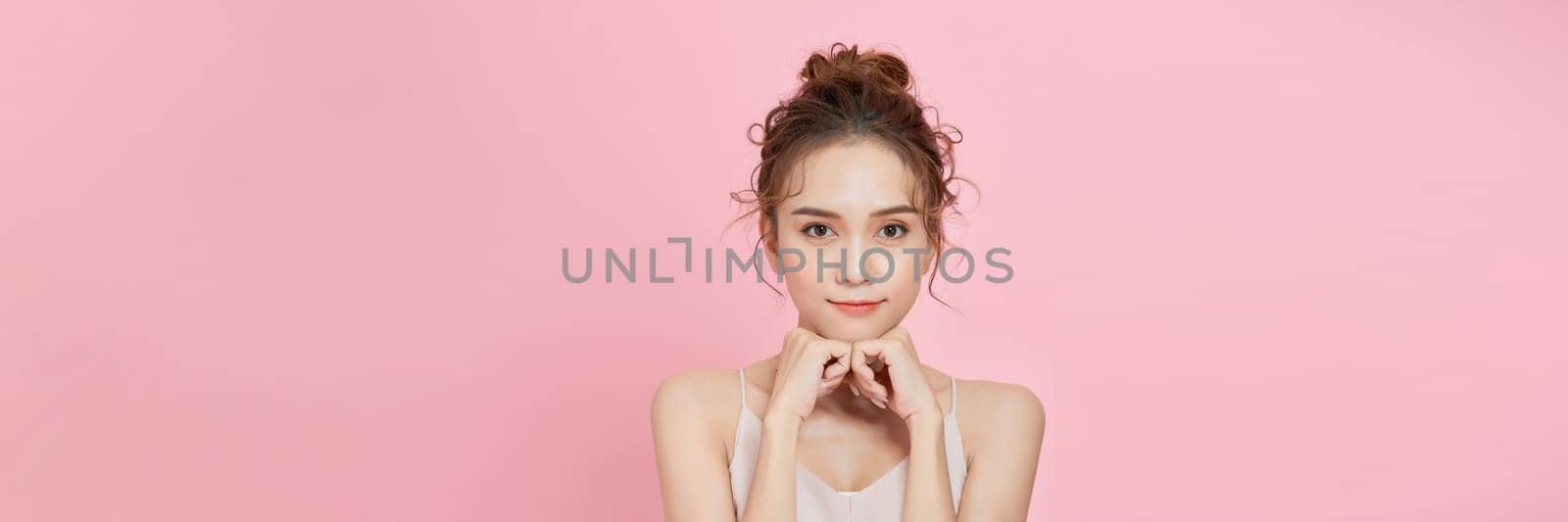 Portrait of beauty asian woman with fair perfect healthy glow skin hand touching chin on pink background