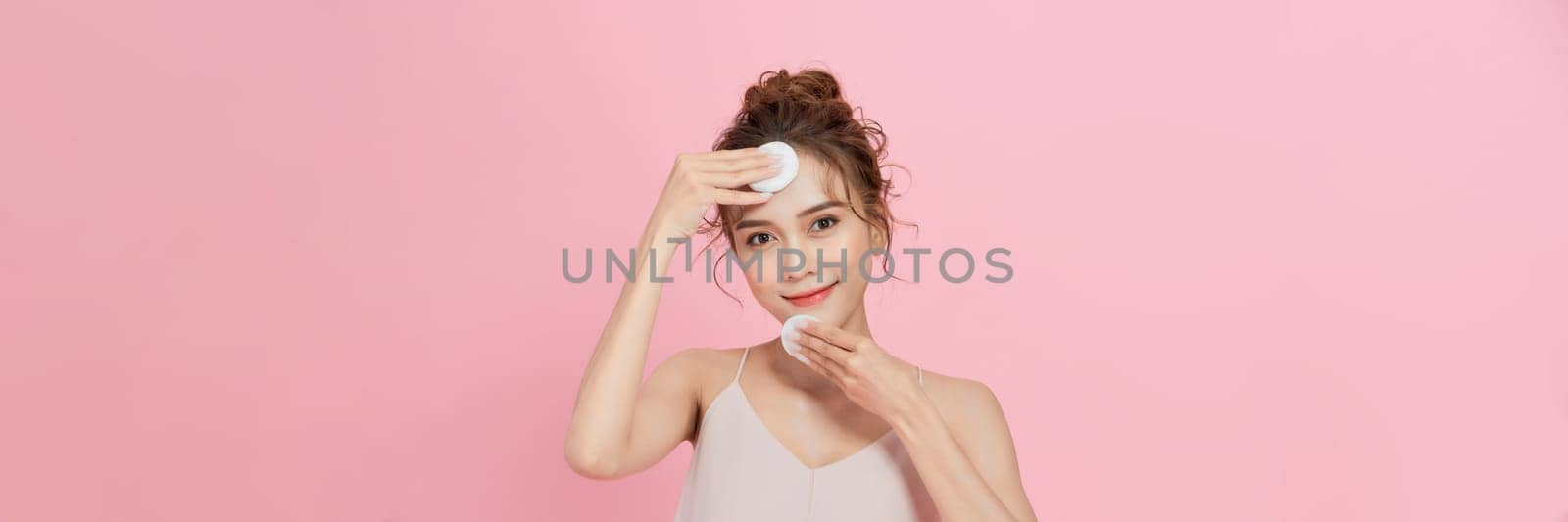 Woman removing makeup, holds cotton pads near face.  by makidotvn