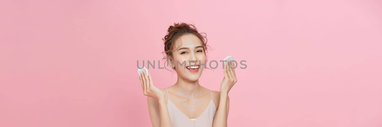 Attractive beauty young asian woman clean skin with cotton pad removing make up on pink background. by makidotvn