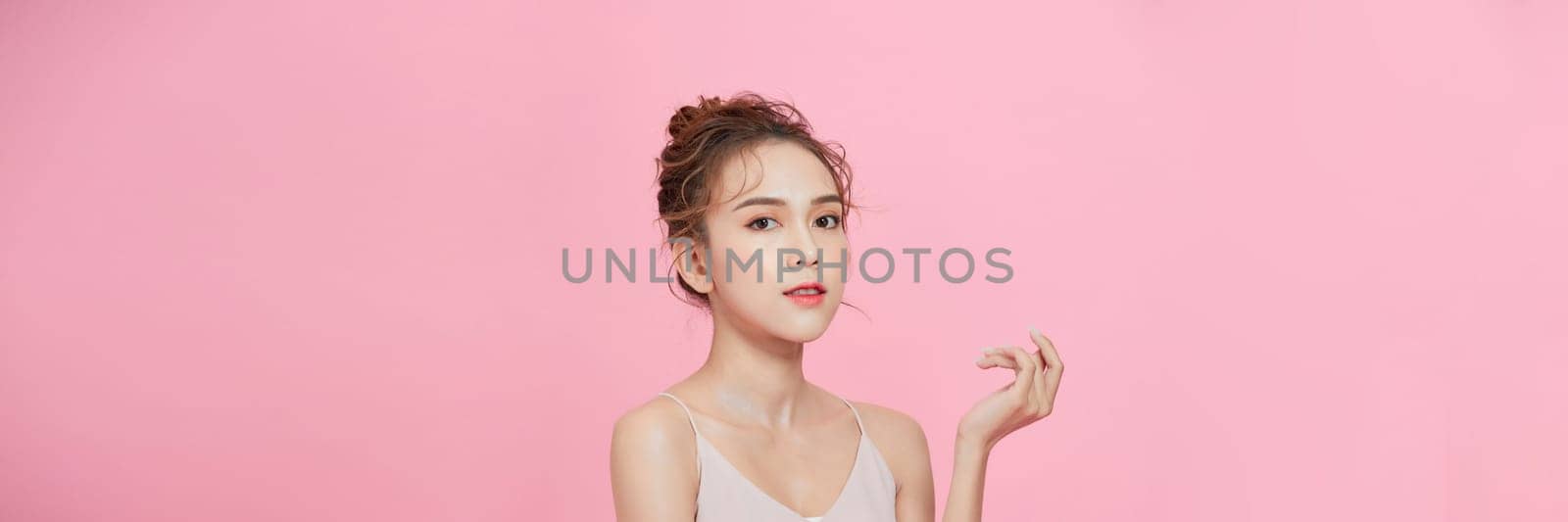 Portrait photo of asian female show her beauty skin care on pink background. by makidotvn