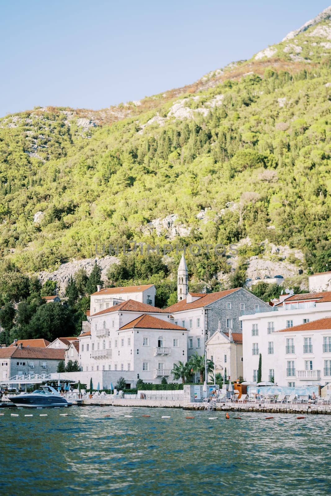 View from the sea of ancient houses at the foot of the mountains. Perast, Montenegro. High quality photo