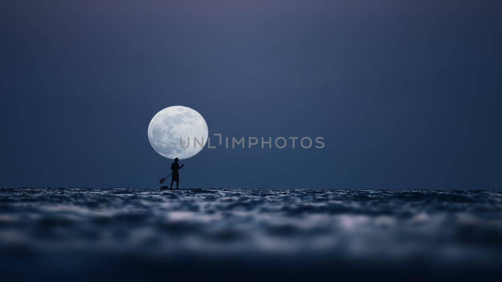 Silhouette of a man on the paddleboard against the rising moon. Paddleboard in the sea at night, side view . Young man on paddle boarding during a beautiful full moon. Paddle-boarding by open water.