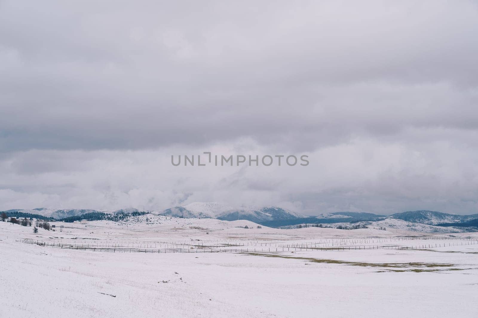 Snowy pastures in a mountain valley with wooden fences. High quality photo