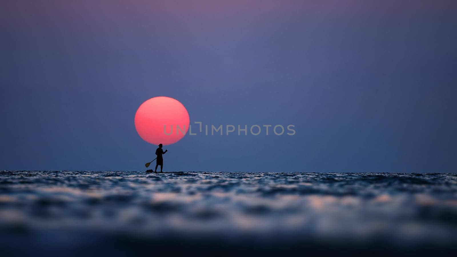 Silhouette of a man on the paddleboard against the setting sun. Paddleboard in the sea at sunset, side view . Young man on paddle boarding during a beautiful sunrise. Paddle-boarding in evening by EvgeniyQW