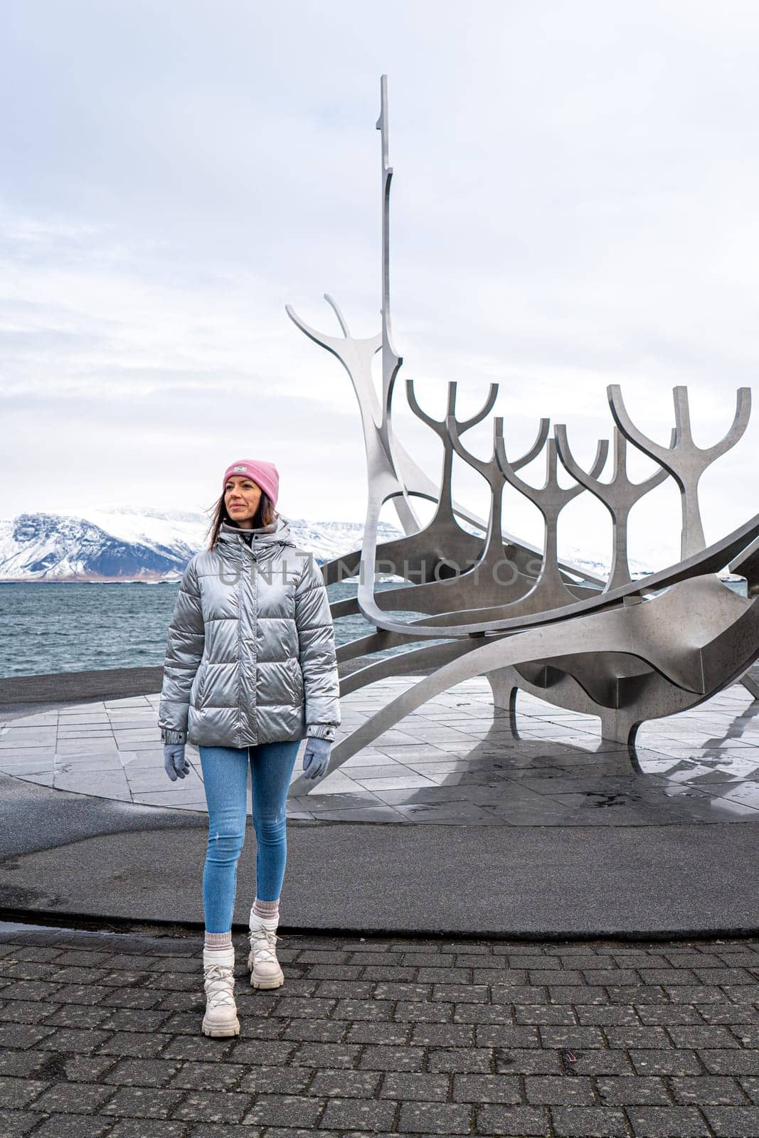 Woman in metallic silver coat next to the Sun Traveler in Reykjavik