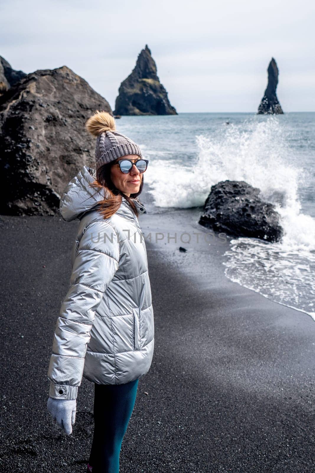 Woman with silver coat and beanie on the black beach of Reynisfjara, Iceland by LopezPastor