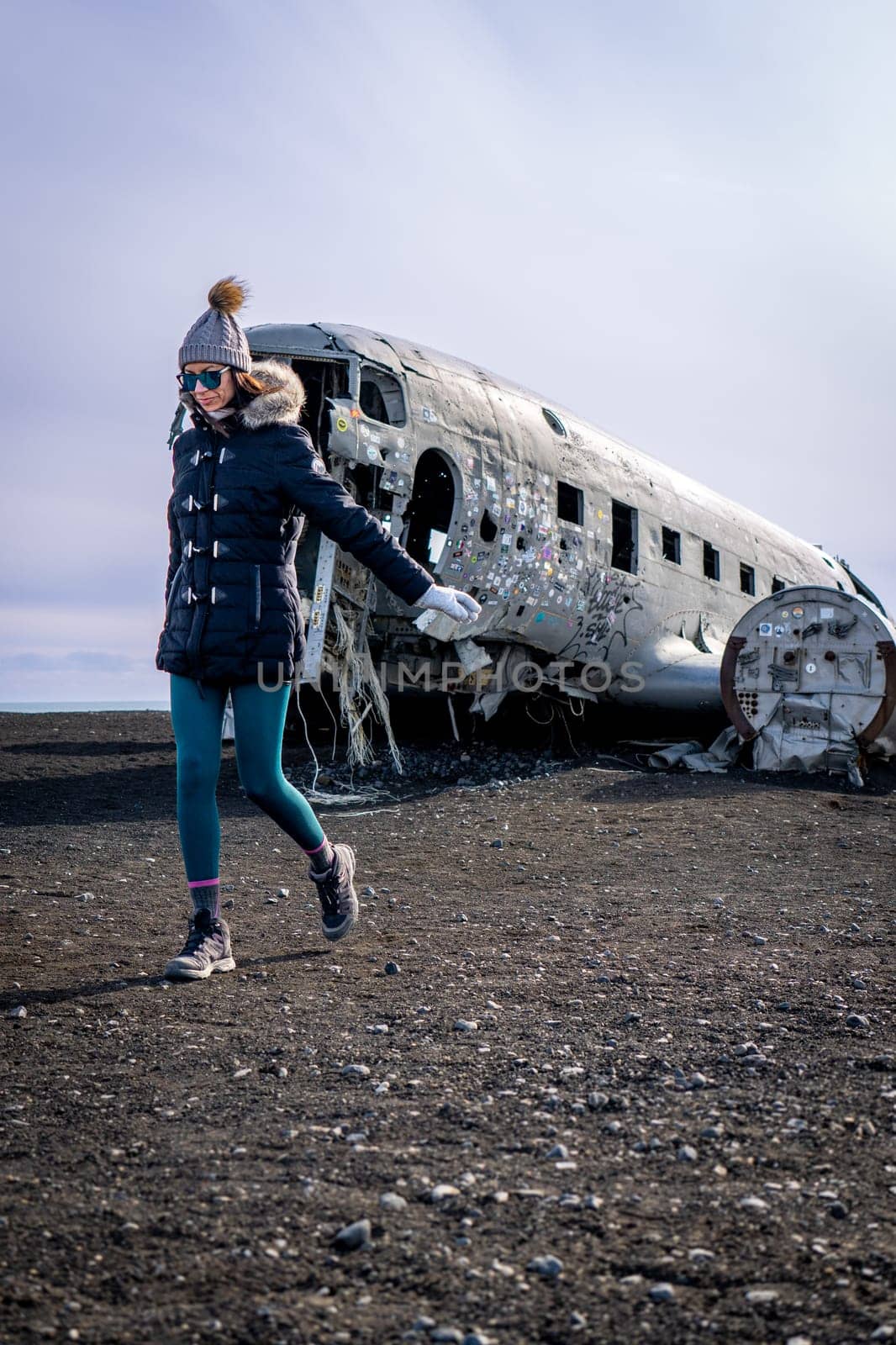 Woman walkin next to a plane wreckage in Iceland