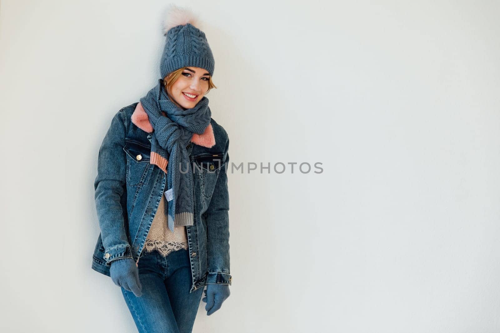 Woman in winter clothes and hat posing on white