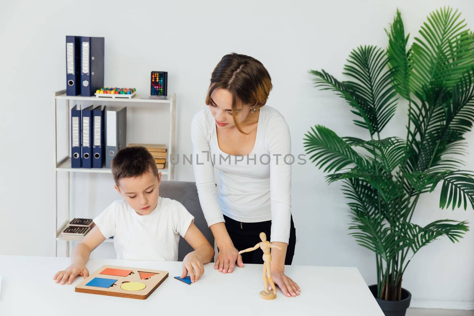 A boy with a teacher learns in the psychologist's office