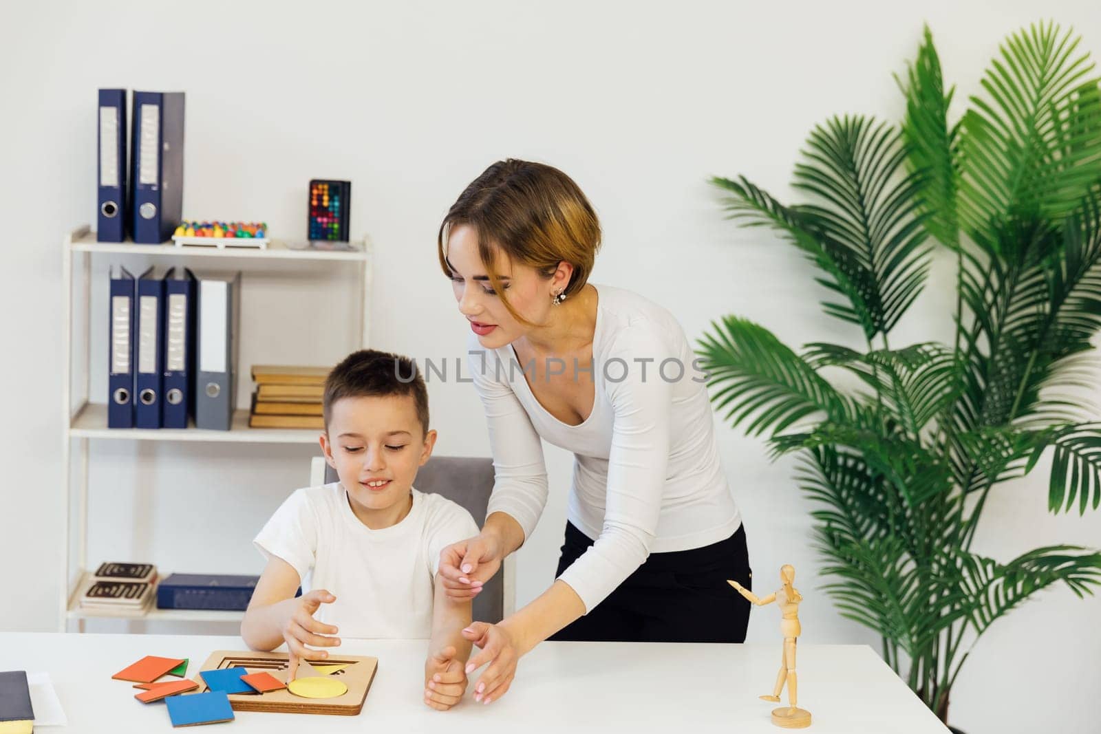 A boy with a teacher learns develops in the psychologist's office by Simakov