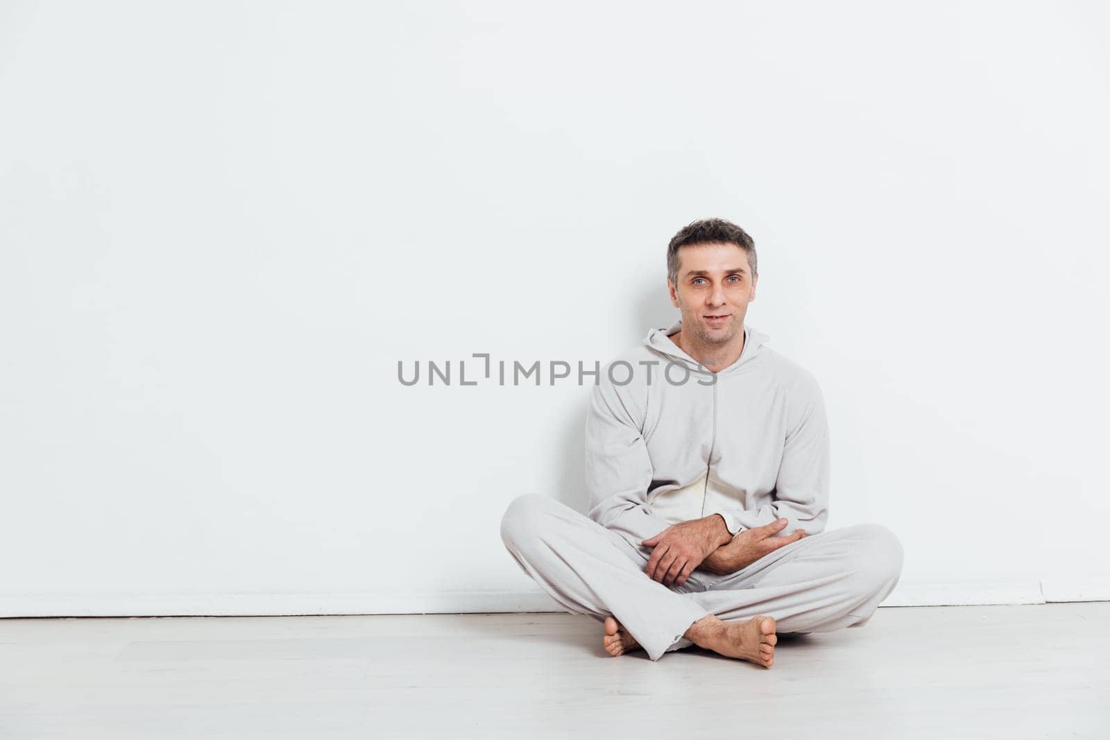 Man in pajamas sitting in a bright room against a white wall