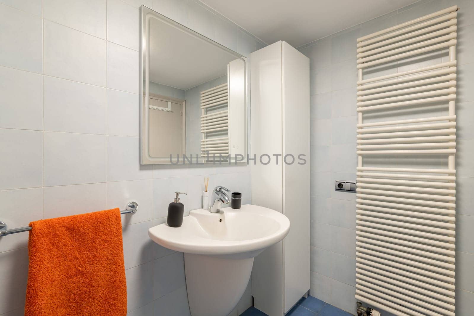 Mirror, sink and towel dryer in modern tiled bathroom by apavlin