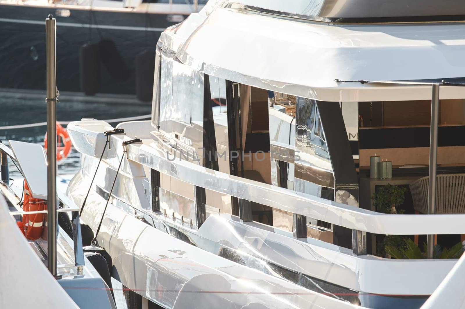 Close up footage of a relaxation area on the open teak deck of an expensive megayacht at sunny day, with awnings stretched over the deck to protect from the sun, wealth life, table and chairs. High quality photo