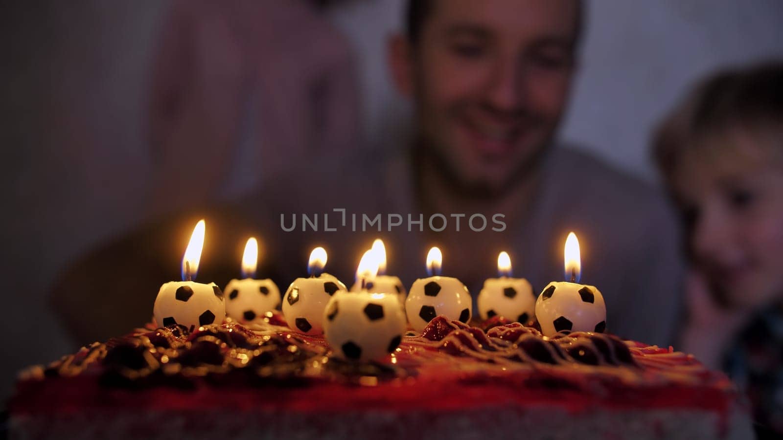 Father football player lights a cake with soccer candles with children