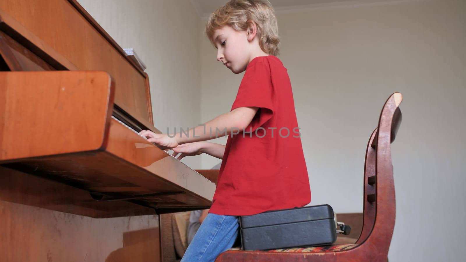 An eight-year-old boy plays the piano at home
