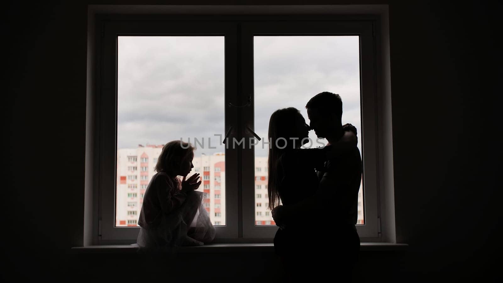 Silhouette of lovers with children on the background of windows from a new apartment. by DovidPro