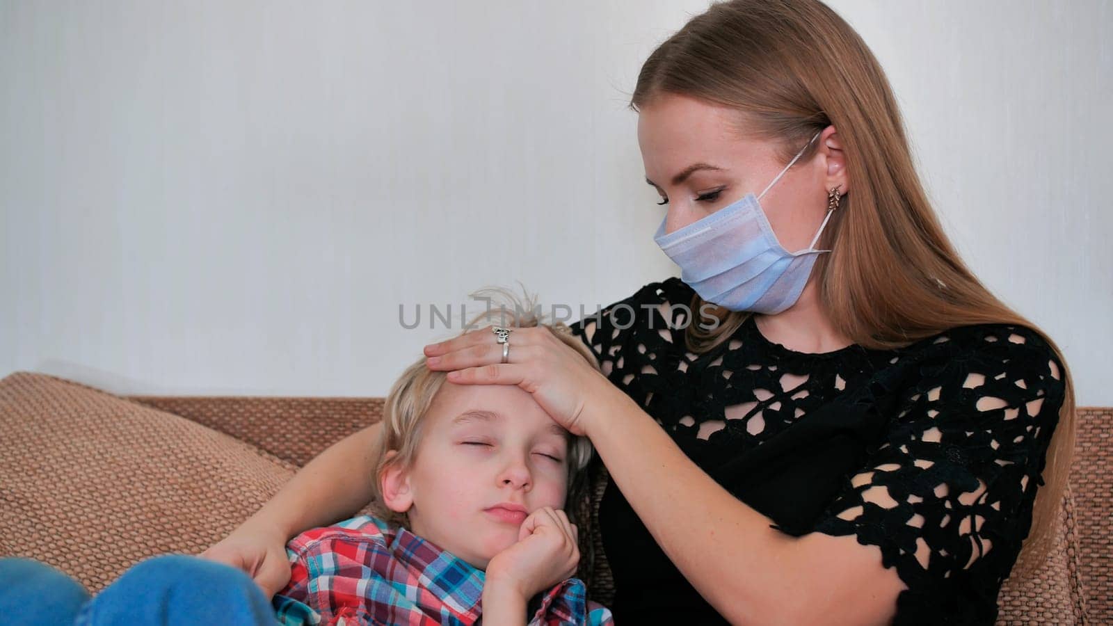 A caring mother in a bandage measures the temperature of her son. by DovidPro