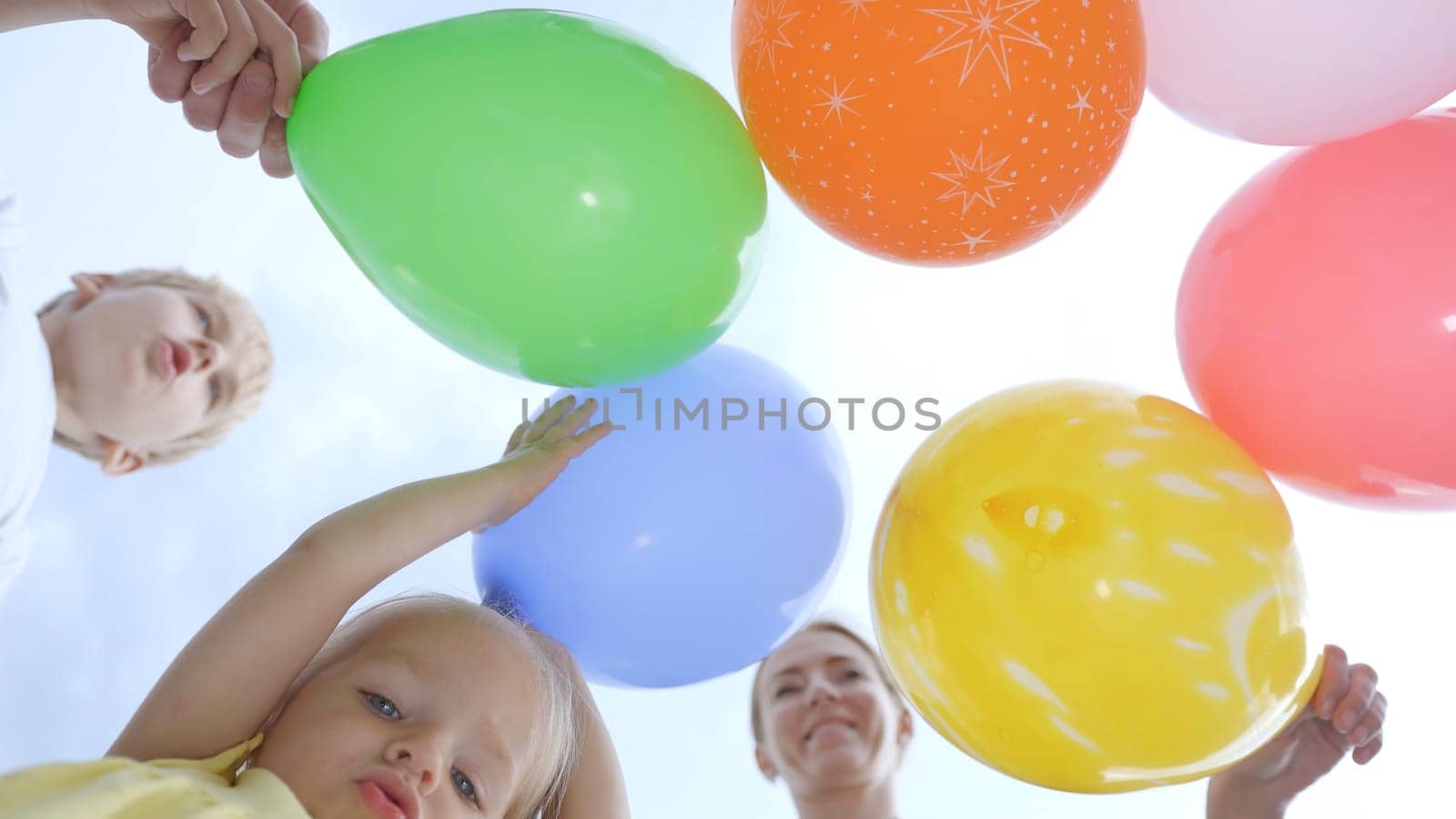 Family with colorful balloons on the street. by DovidPro