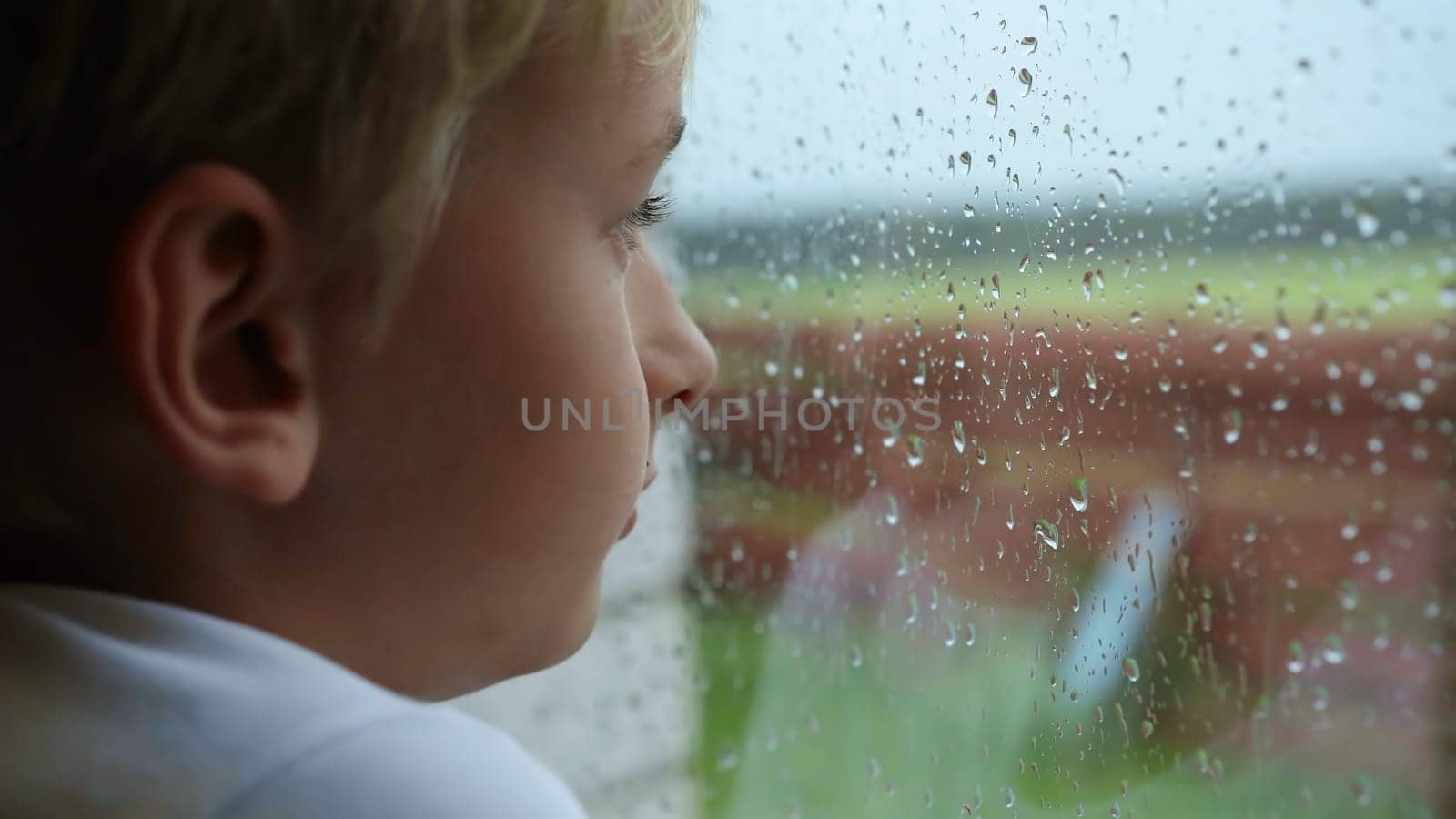 A little boy looks out the window during the rain