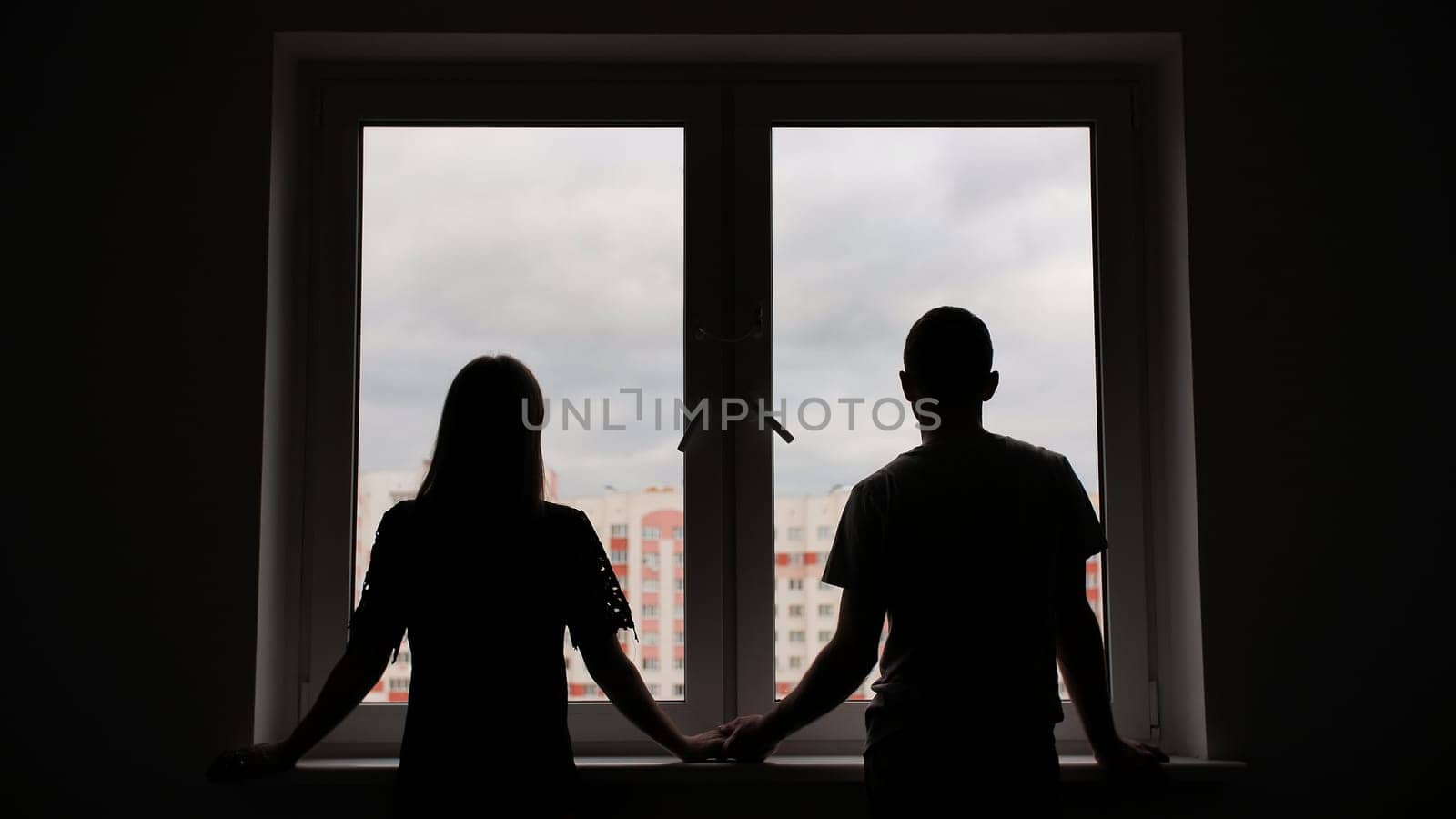 The silhouette of the newlyweds on the background of windows from a new apartment