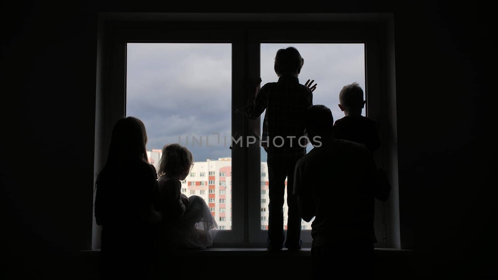 Silhouette of a large family on the background of a window in a new apartment. Quarantine concept. by DovidPro