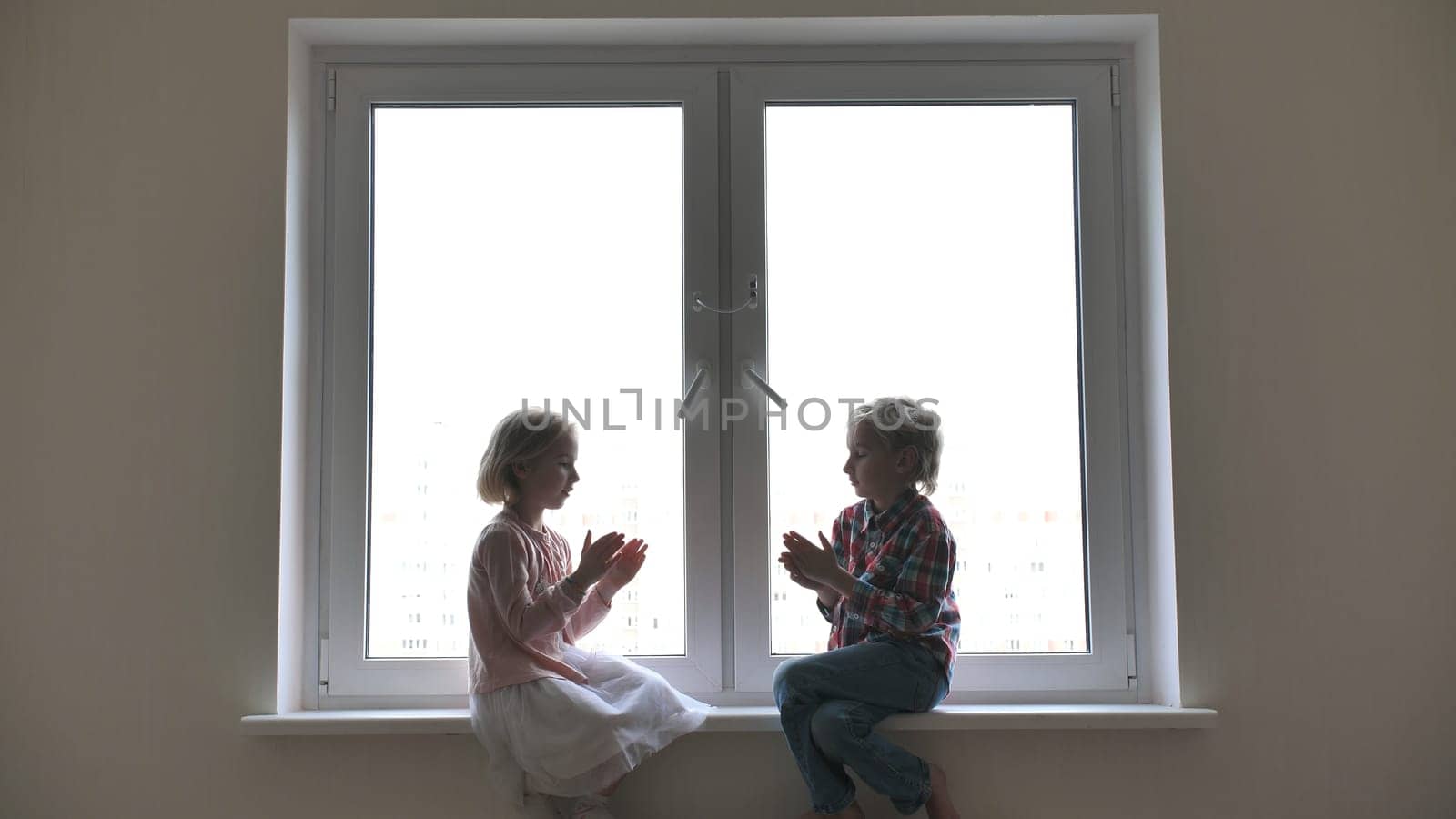 Silhouette of children playing hand on window sill