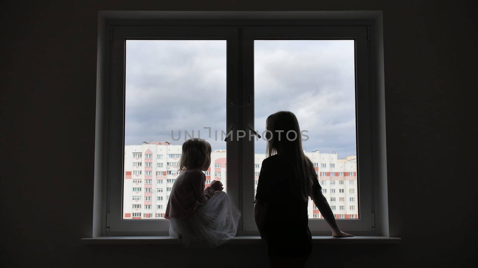 Mother comes to her lonely daughter who is sitting by the window. by DovidPro