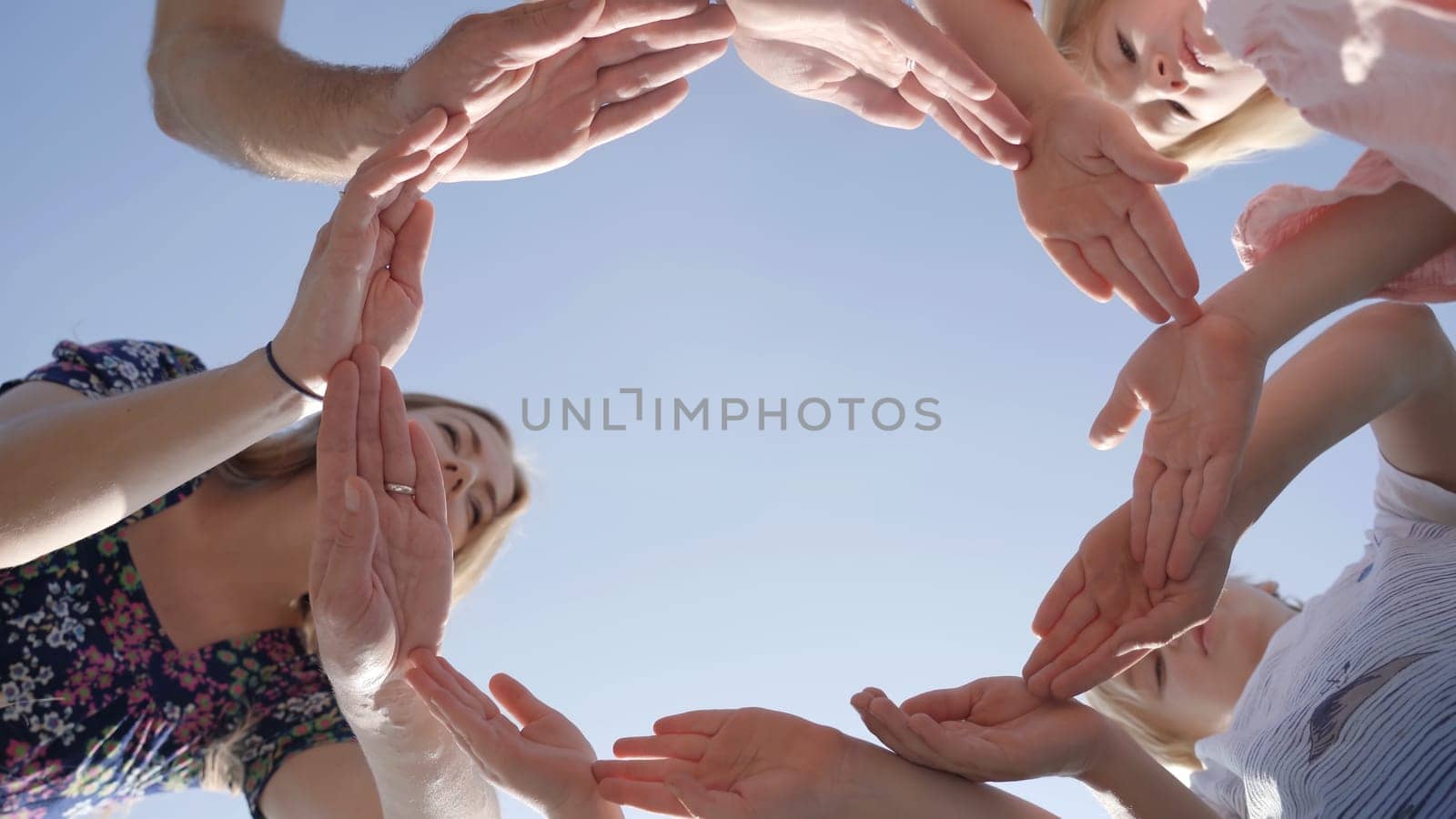 A friendly family makes a circle out of their hands and looks into it