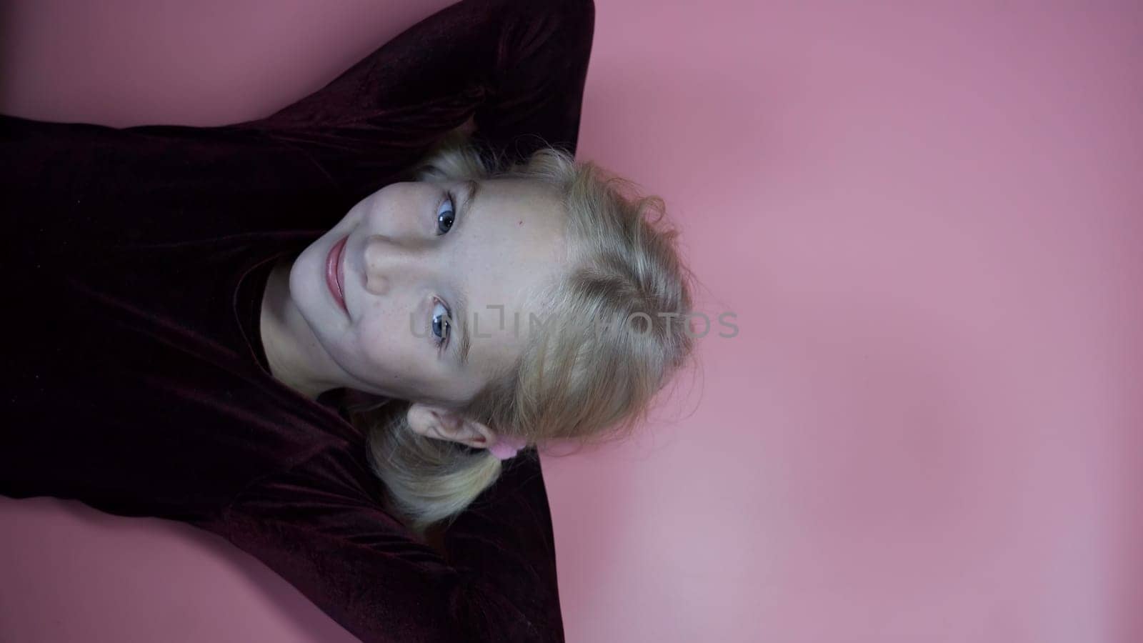 Portrait of a lying little seven year old girl on a pink background. by DovidPro