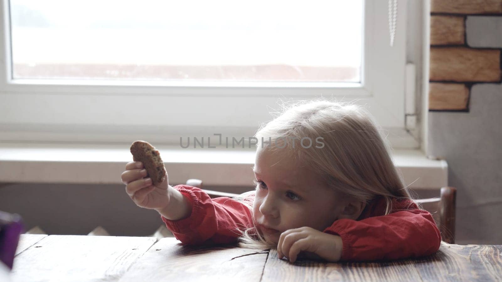 Little beautiful girl eats cookies at home