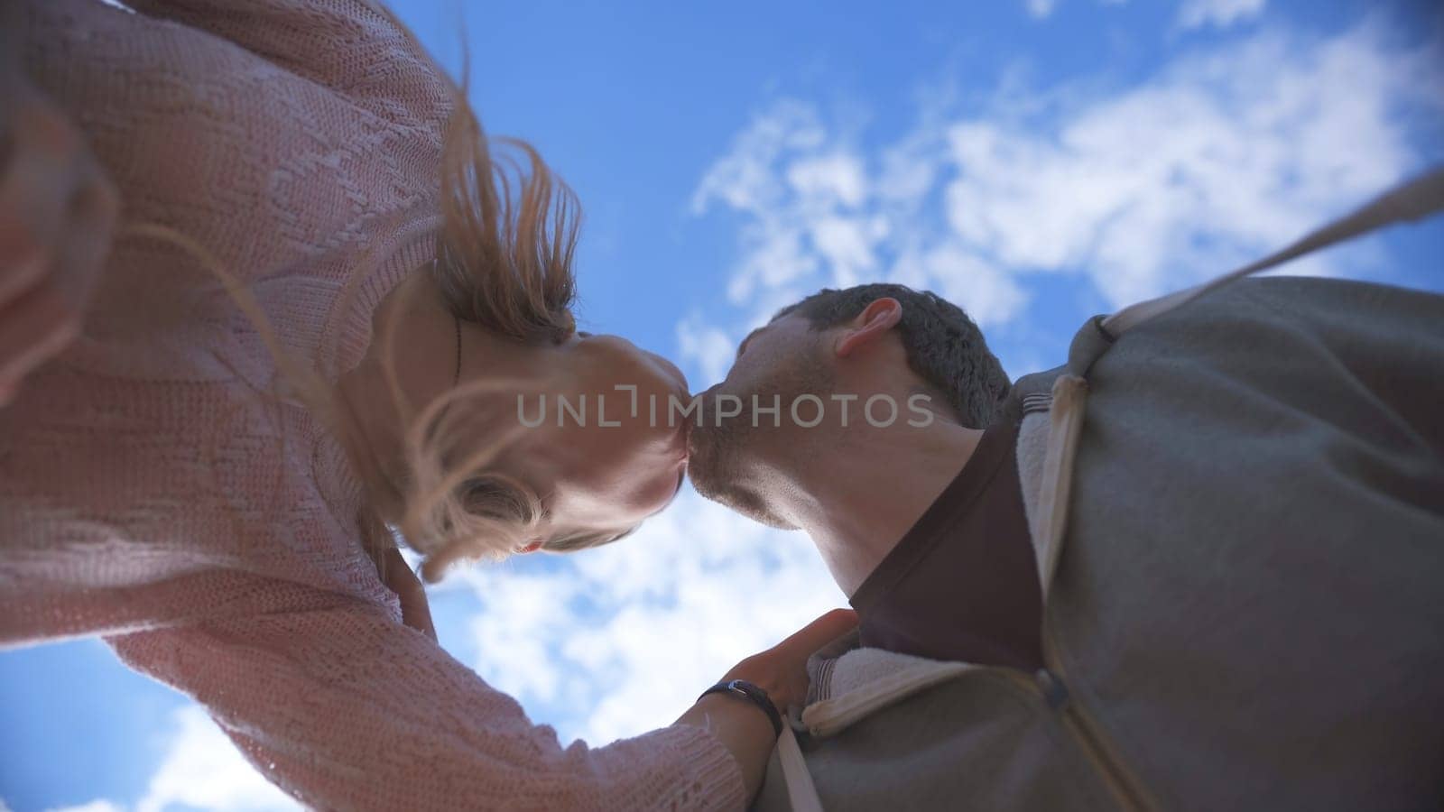 Amorous couple kissing on a background of blue sky