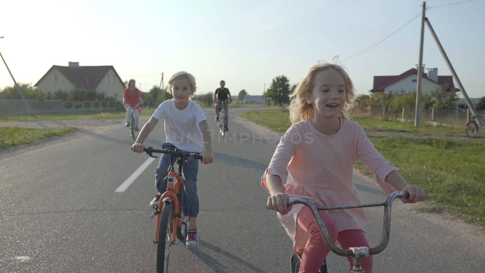 Cheerful children on bicycles in the village. by DovidPro